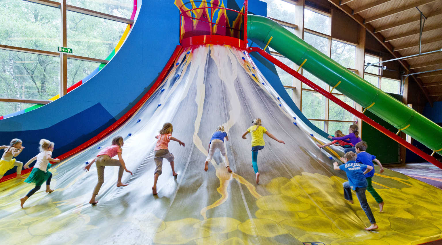 Kids climbing up the slipping slope in the indoor play centre at Vakantiepark de Bergen campsite, Netherlands
