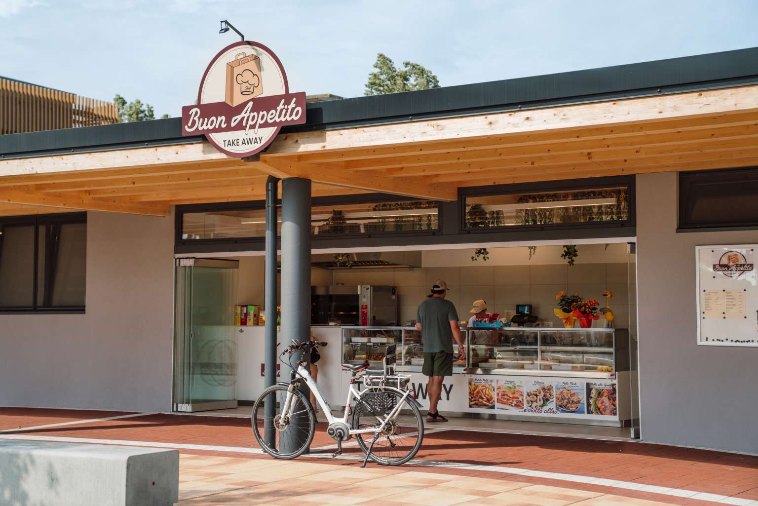 Man with bike stood at the Take away booth at Pra'delle Torri campsite in the Adriatic