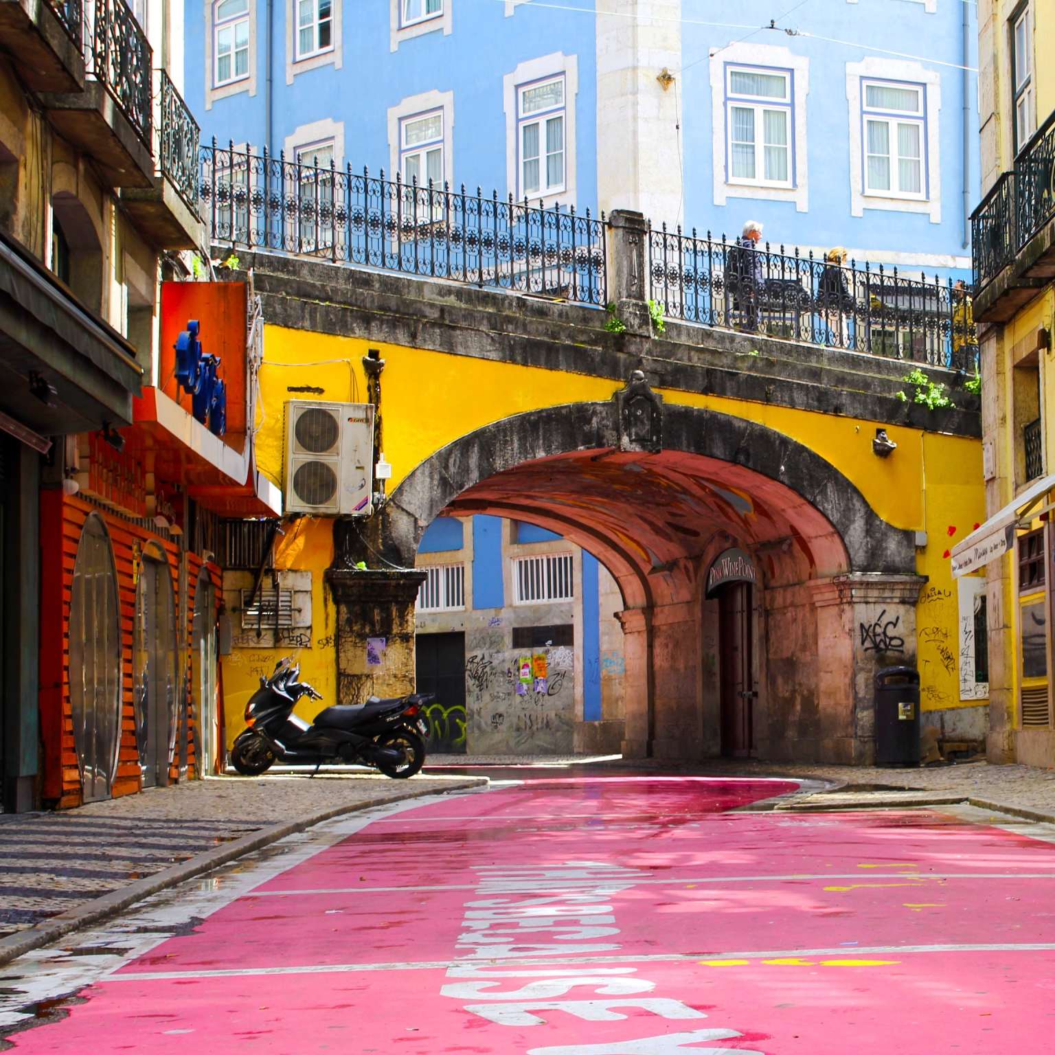 yellow bridge over a pink road in Lisbon, Portugal