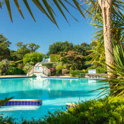 View of jazuzzi, pool, toboggan waterslides, looking through palm trees at la Grande Metairie campsite near Carnac in Brittany
