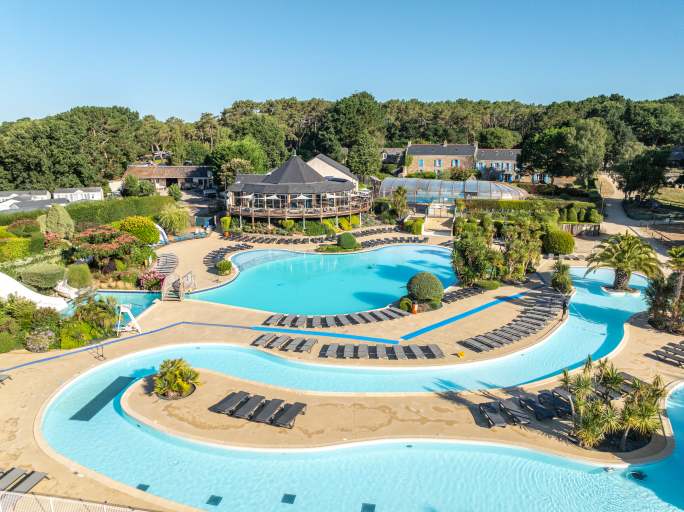 Aerial view of round restaurant building, lagoon pool and snaking lazy river at la Grande Metairie campsite near Carnac in Brittany