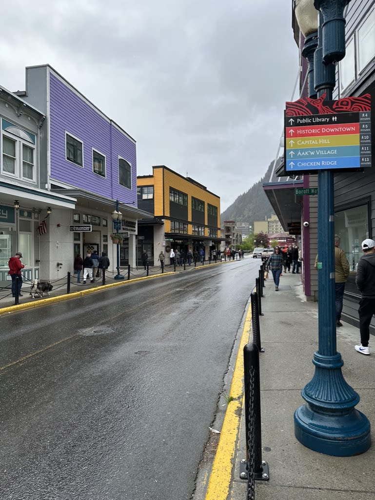 A rainy street in a town with colorful buildings and people walking.