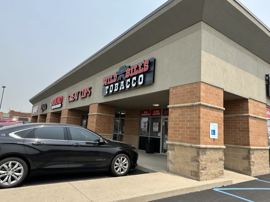 Exterior of a tobacco shop with a black car parked nearby.