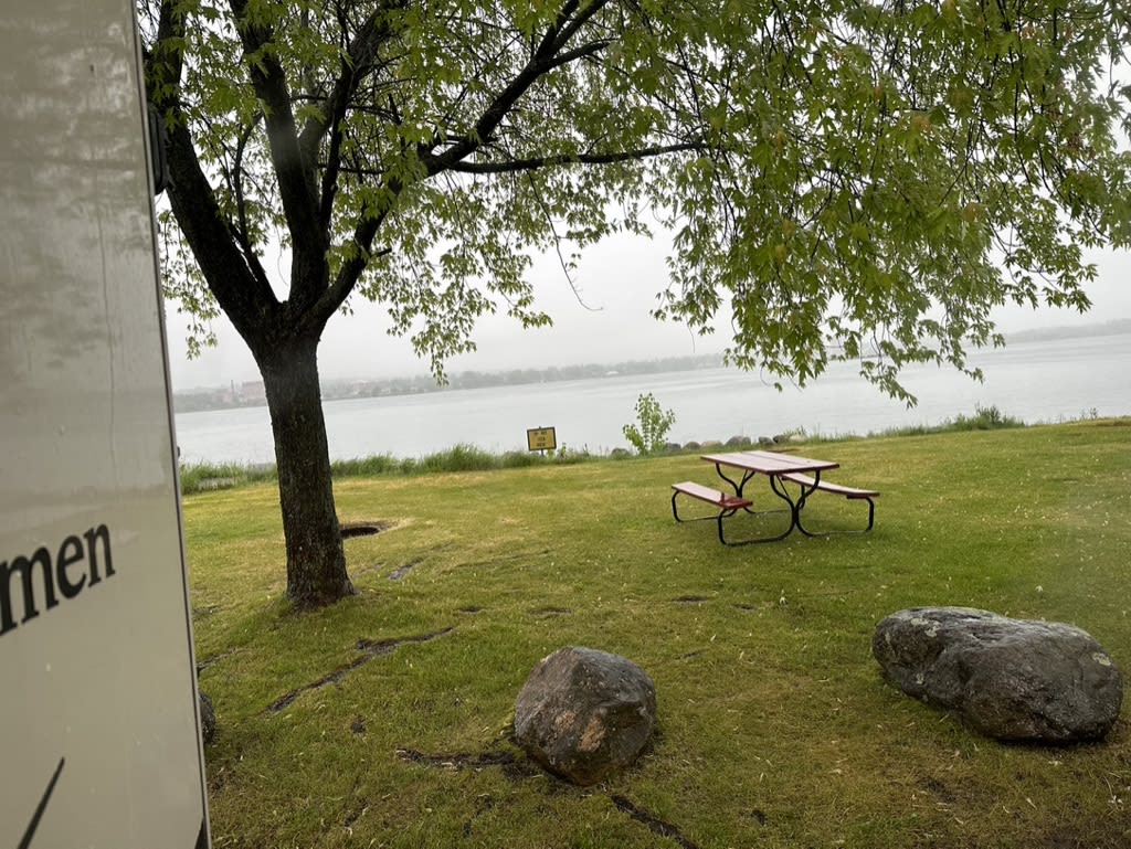 View of a picnic area near a lake under cloudy skies.