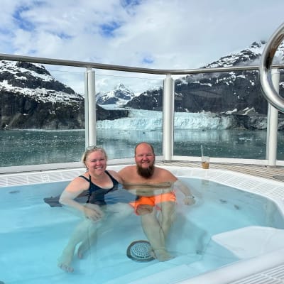 Two people in a hot tub with glaciers in the background.