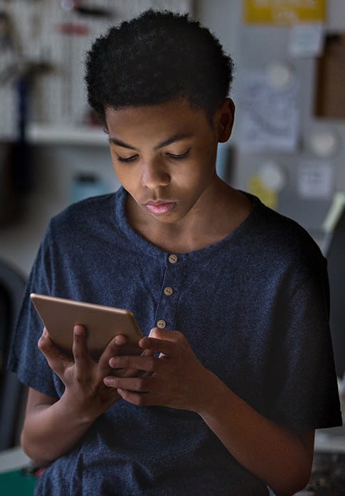 A young teenager readomg on his ipad