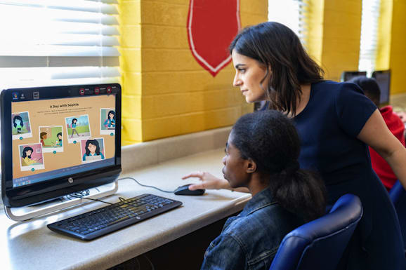 Local Support a teacher helping a student navigate a web course on her class desktop computer