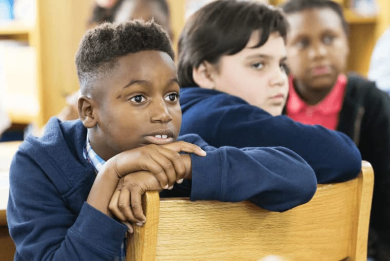 Two students sharing a chair very engaged in a group activity.