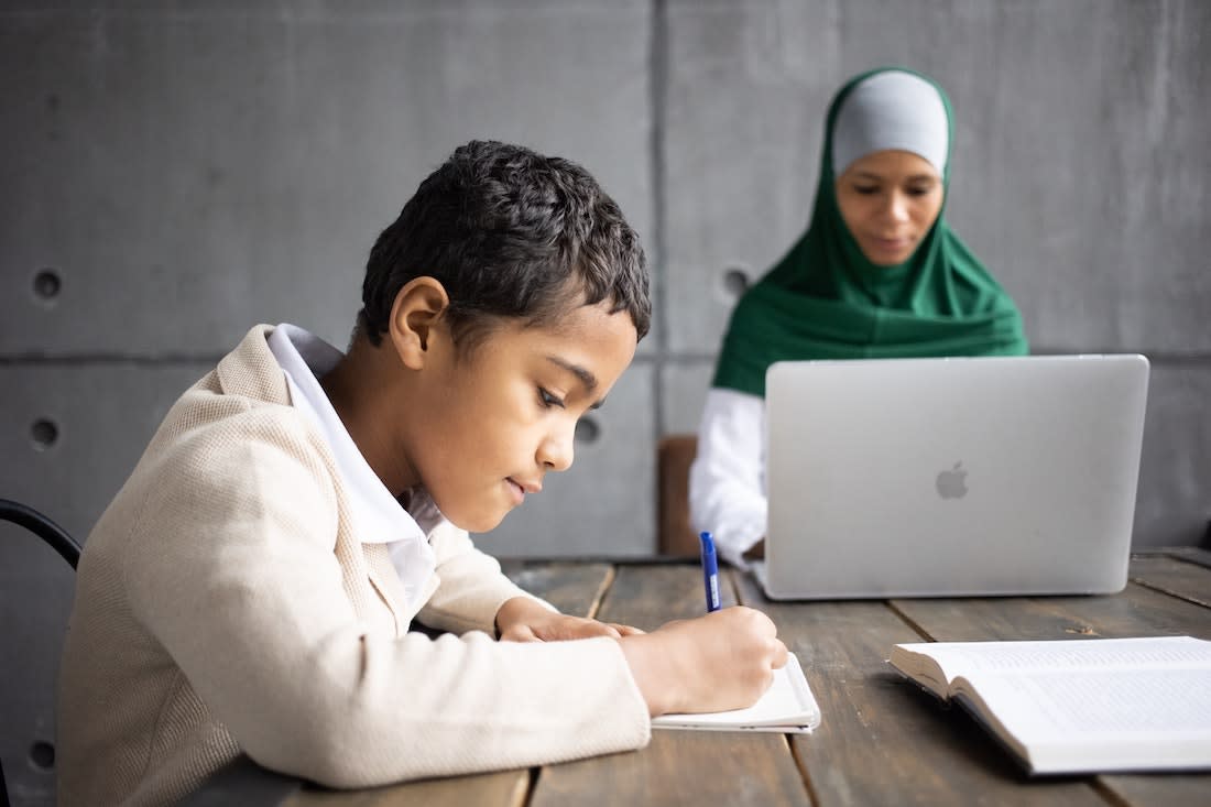 Parent working on laptop while child is working on schoolwork