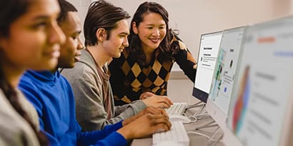 A teacher helping a student on a computer in class