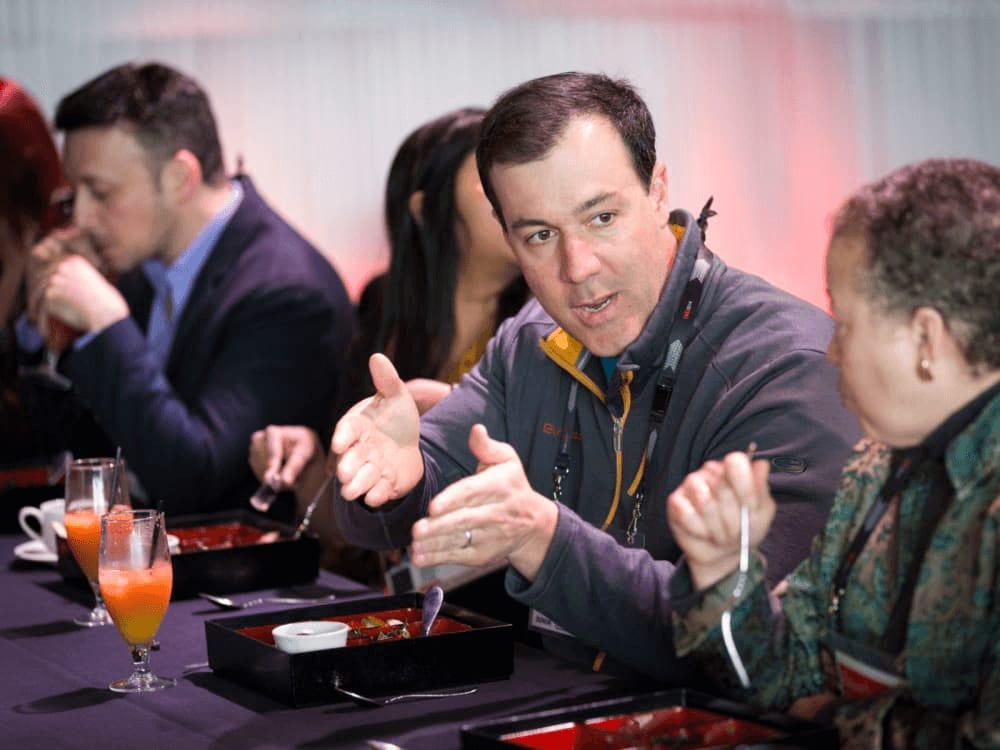 Jon Chapman speaking to a woman at an dinner event.