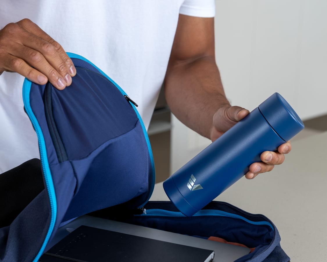 Male putting Ever Vessel Multi Blue water bottle into work back pack