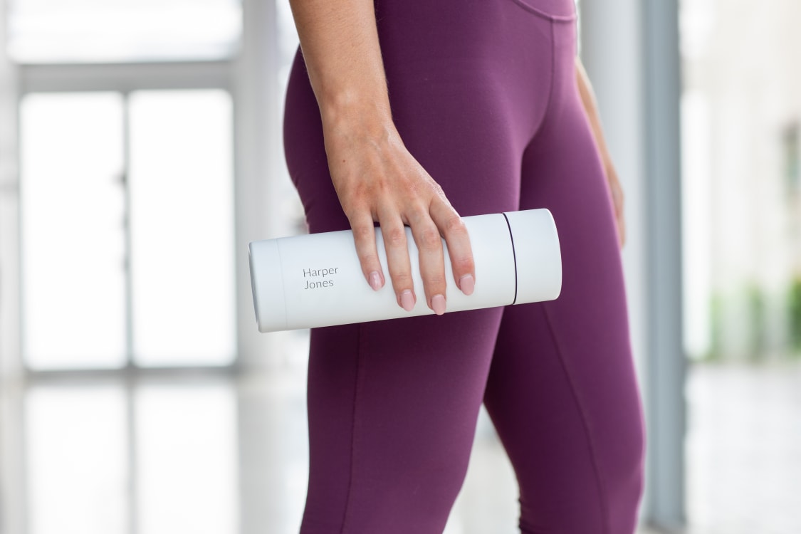 Lady using an Ever Vessel Multi White Sand bottle engraved with her name on the side at the gym