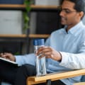 Male sitting in chair holding an Ever Vessel Glass Multi Blue water bottle