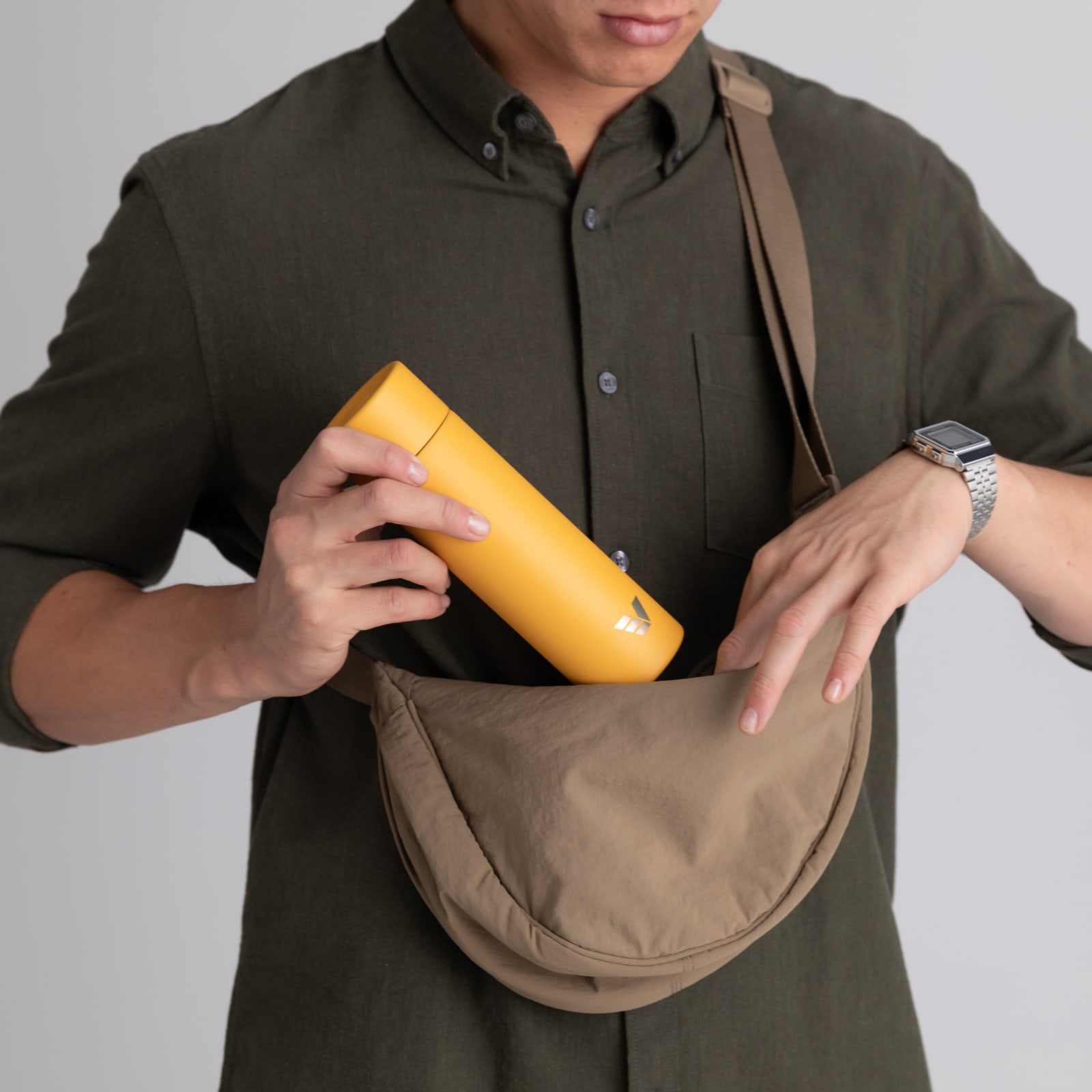 Man putting Ever Vessel Mini Yellow water bottle into a bag