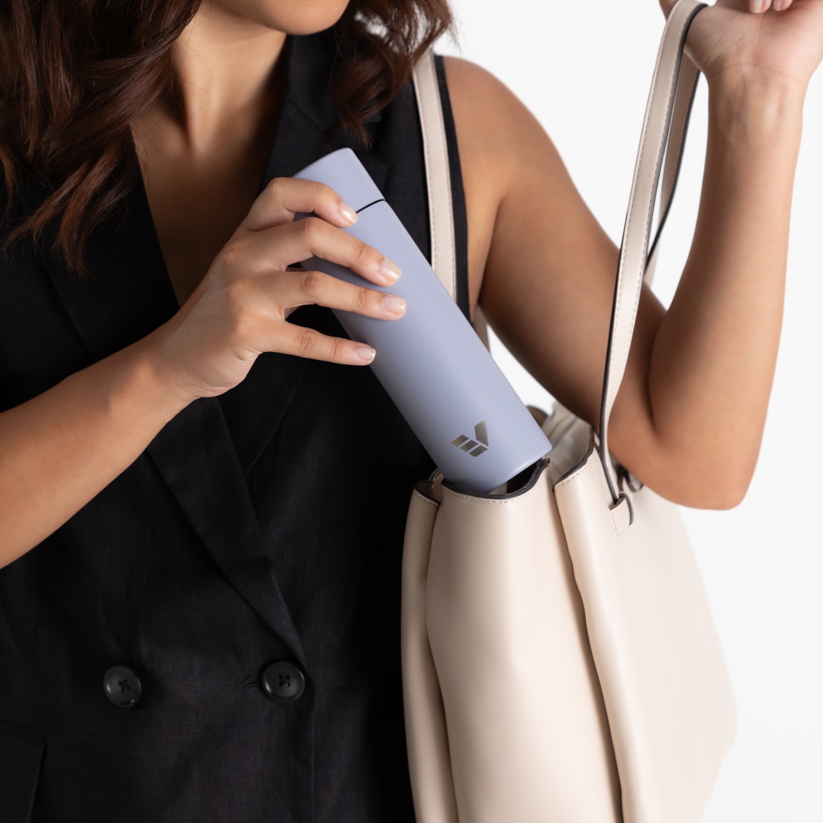 Female putting Ever Vessel Mini Lilac water bottle into handbag