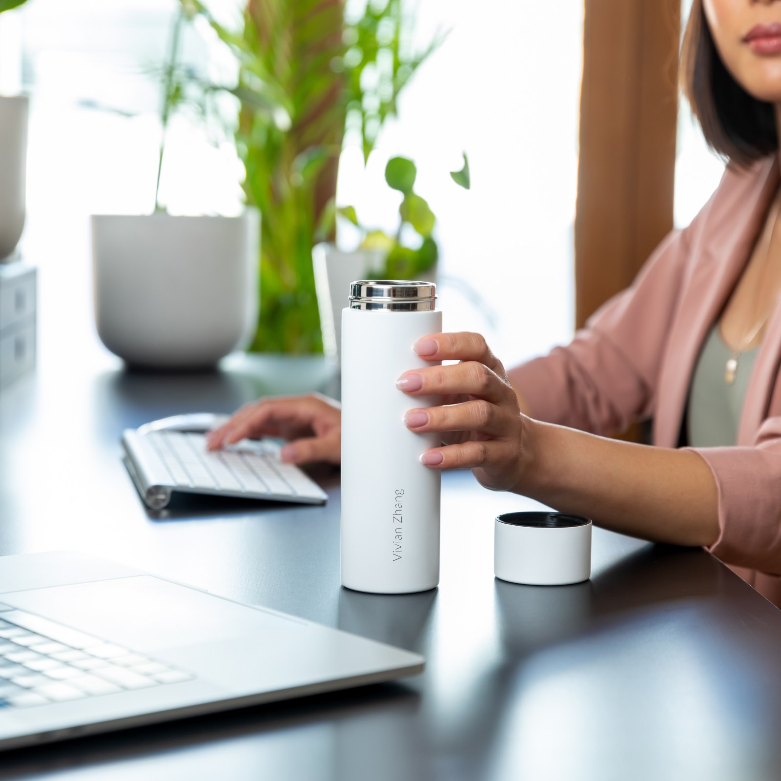 Lady holding an Ever Vessel Mini White Sand water bottle laser engraved with her name on it at her deak