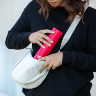 Female putting Ever Vessel Mini Red water bottle into side satchel