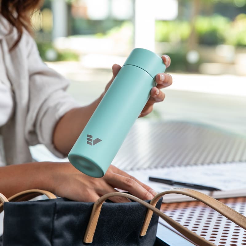 Female putting an Ever Vessel Mini Mint green water bottle into a bag