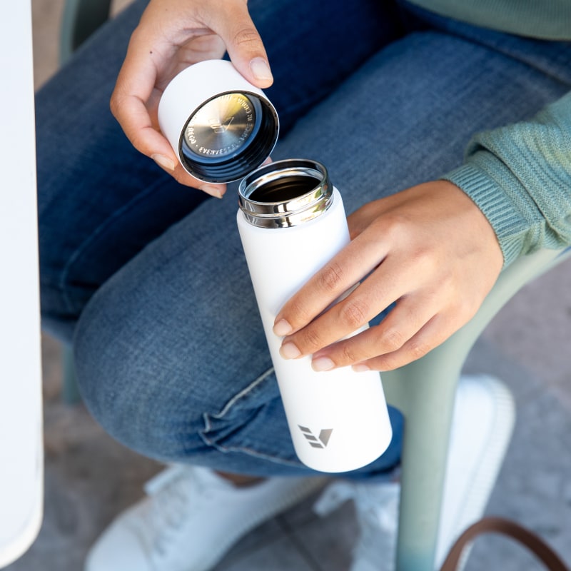 Female holding Ever Vessel Mini White Sand water bottle with lid off