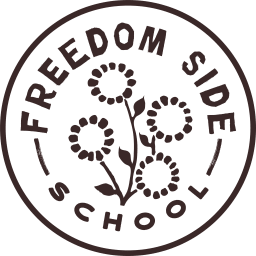 hand stiched circle of navy fabric with flowers blooming along the edges, with the words "Freedom Side School" stiched in yellow thread