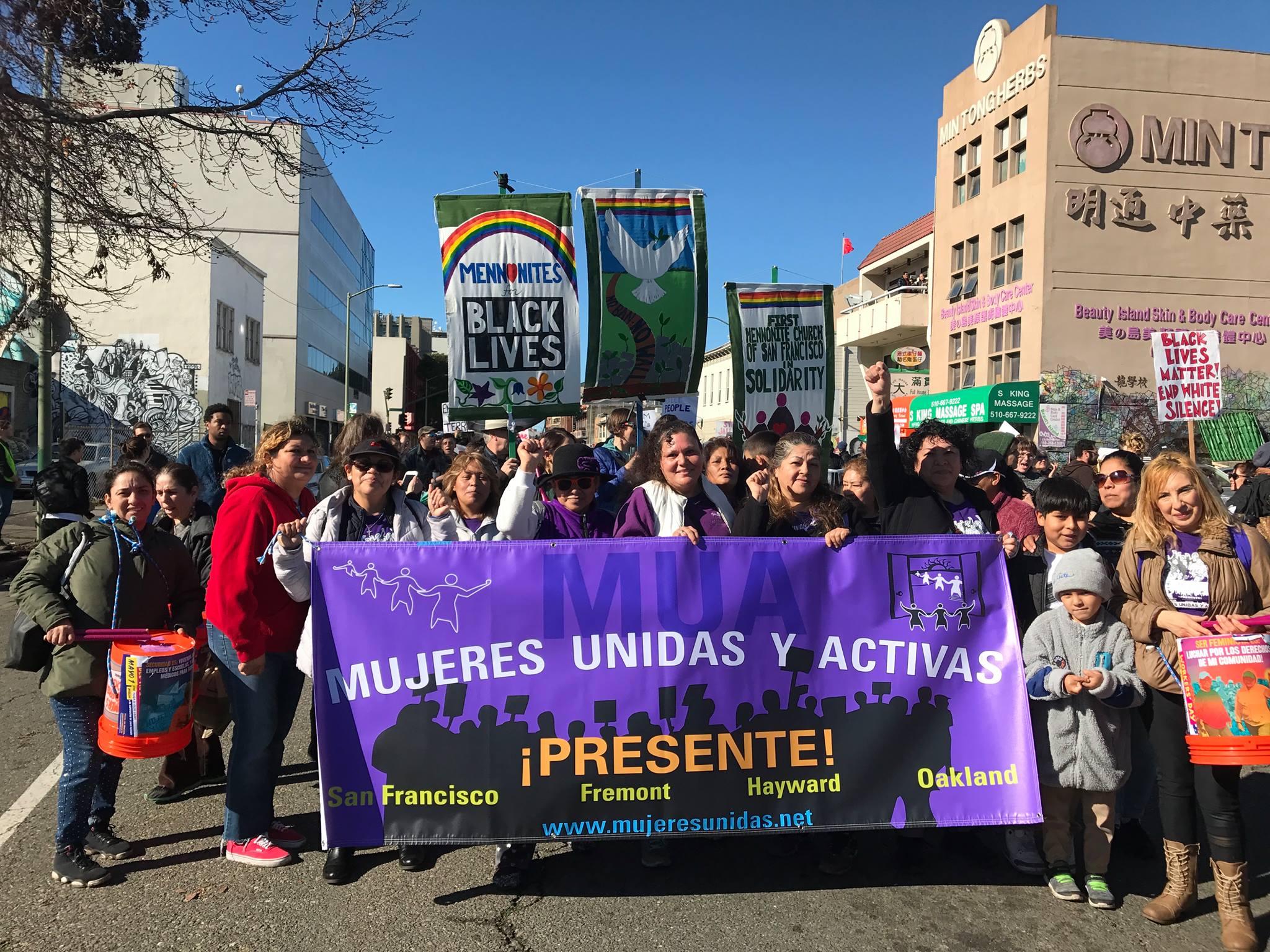 Women and children marching with a MUA banner   