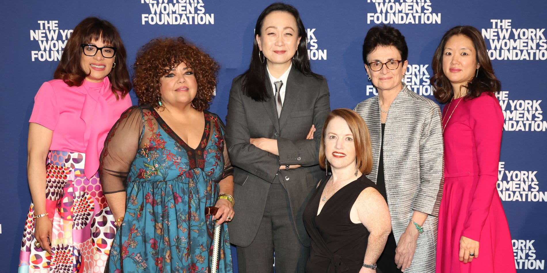 A group photo of six people standing in front of The New York Women's Foundation background at a formal event