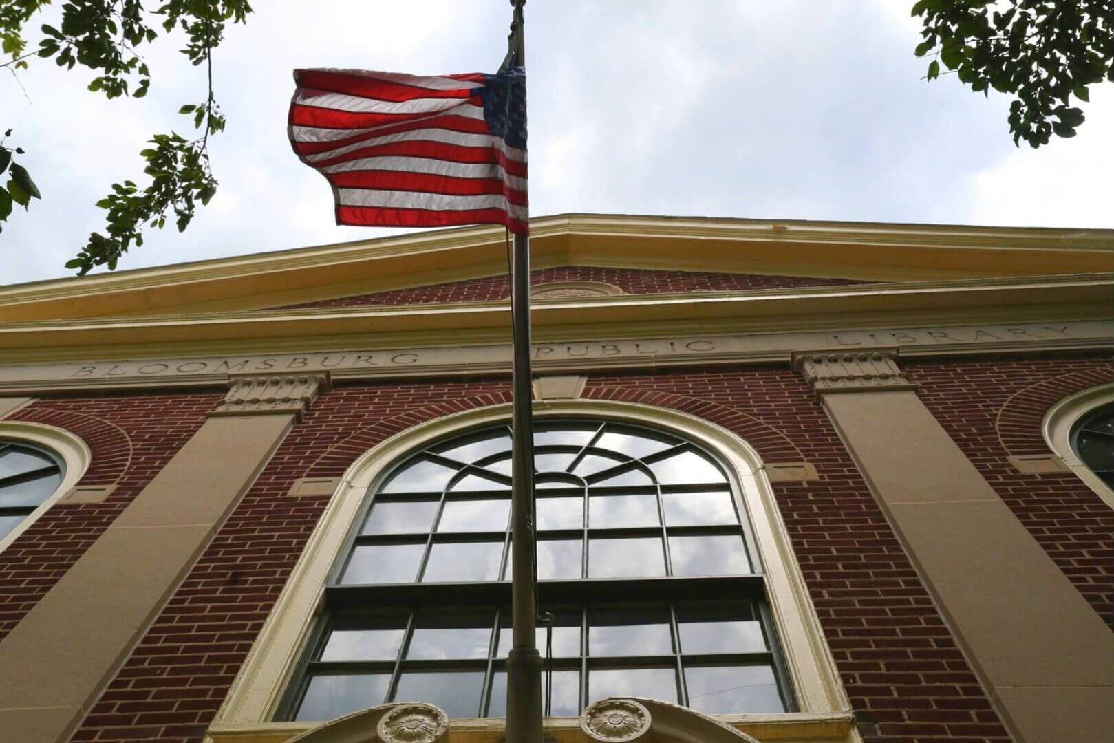 A photo of the Bloomsburg Public Library's second story with the American flag visible.