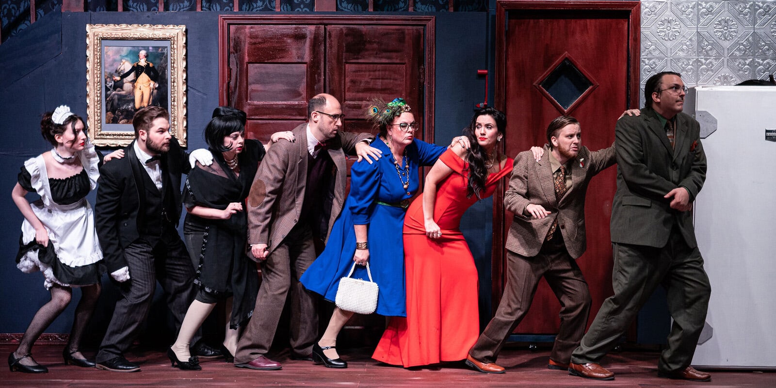 Eight actors in colorful 1950s-style costumes form a humorous line onstage, each leaning forward and peering to the right as if sneaking or eavesdropping. Their outfits include a maid uniform, formal suits, and bright dresses. A painting hangs on the wall behind them, and two wooden doors frame the scene in a classic manor-house set.