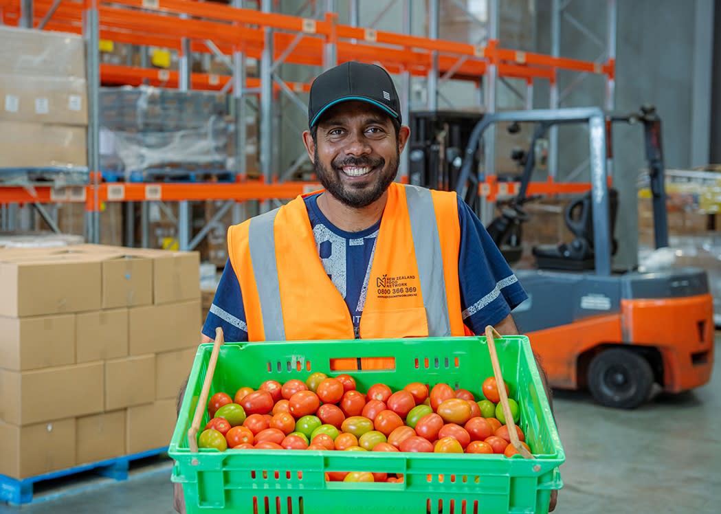 New Zealand Food Network volunteer holding crate of donated apples.