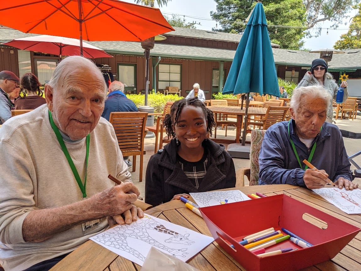 Two seniors working on an art project with a student volunteer.