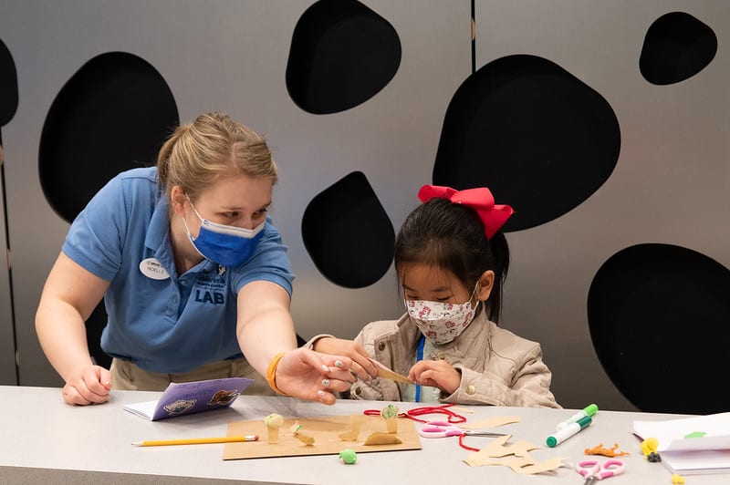Lab staff assisting a child with an experiment.