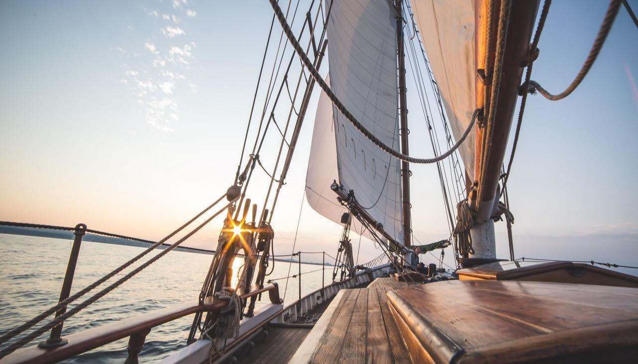 Two masted ship sailing into the sunset.