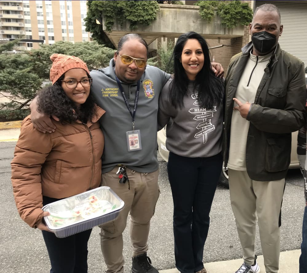 Volunteers for Northwest Community Food pantry are young and middle-aged people who are smiling. One is wearing a winter coat and knit hat.