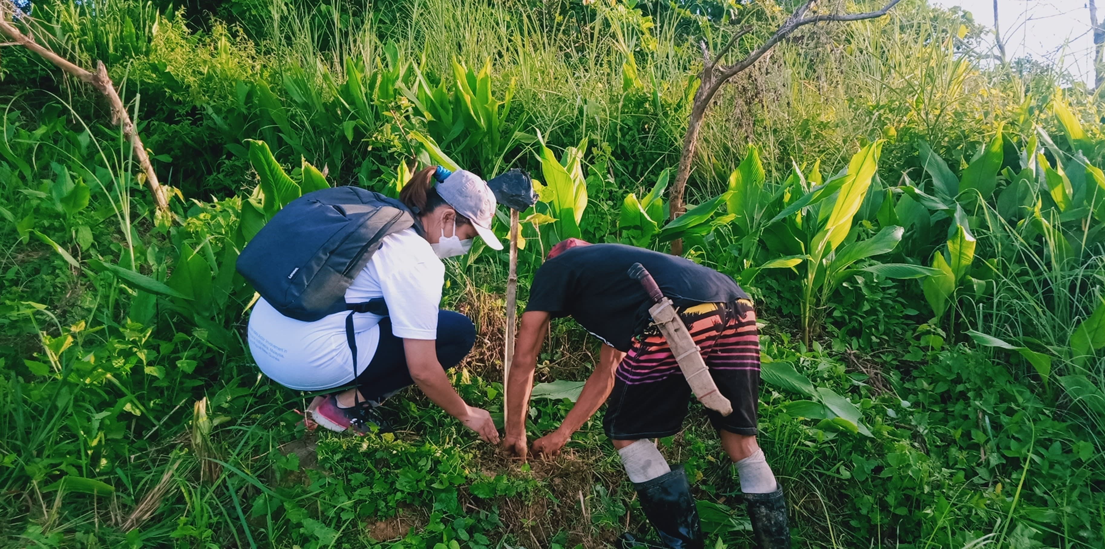 A Haribon volunteer and community partner member planting a seedling together