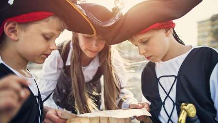 Evian Resort - Trois enfants avec des chapeaux de pirates regardant une carte
