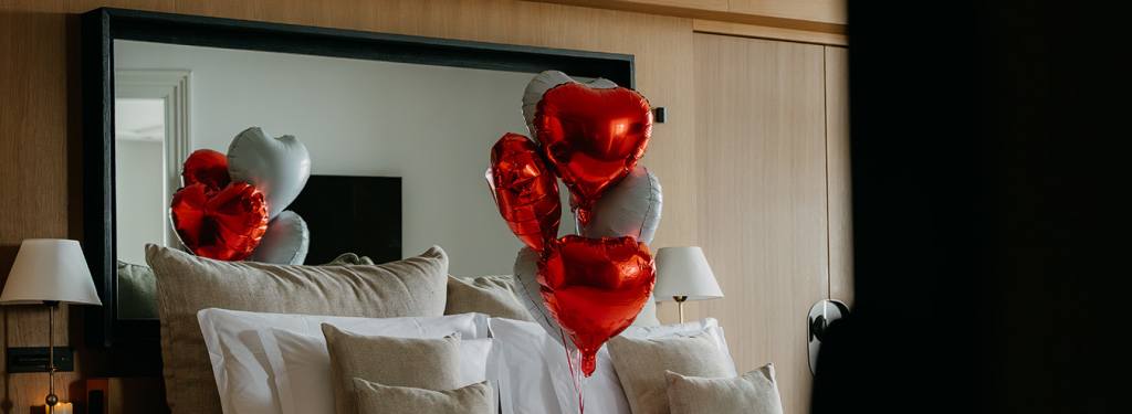 Hôtel Royal Evian Palace 5 étoiles, ballons en cœurs et pétales de roses sur un lit de l'hôtel