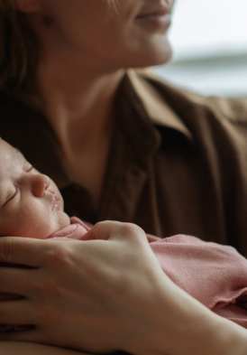 Un bébé emmitouflé dans les bras de sa maman pour l'offre Mon Bel Ange de l'hôtel Ermitage, la retraite postnatale