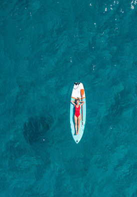 Femme en maillot de bain rouge allongée sur son paddle au milieu du lac Léman