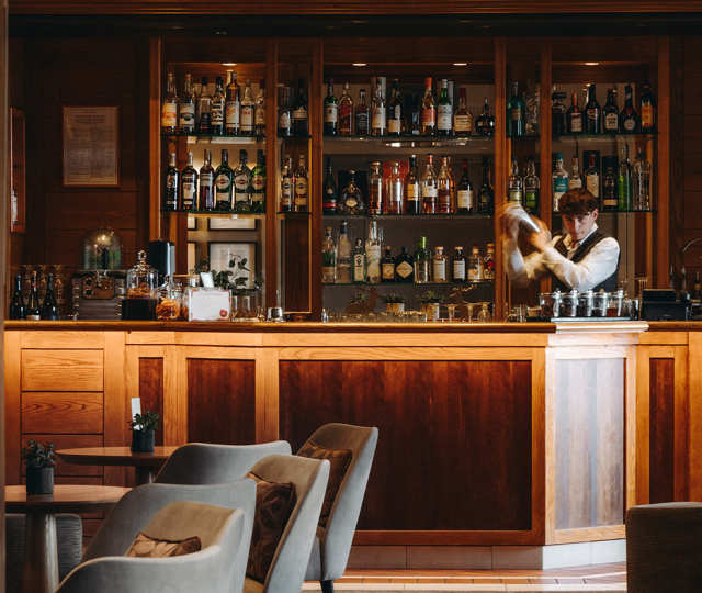 Hôtel Ermitage, 4 étoiles à Evian - Barman créant un cocktail derrière le bar en bois