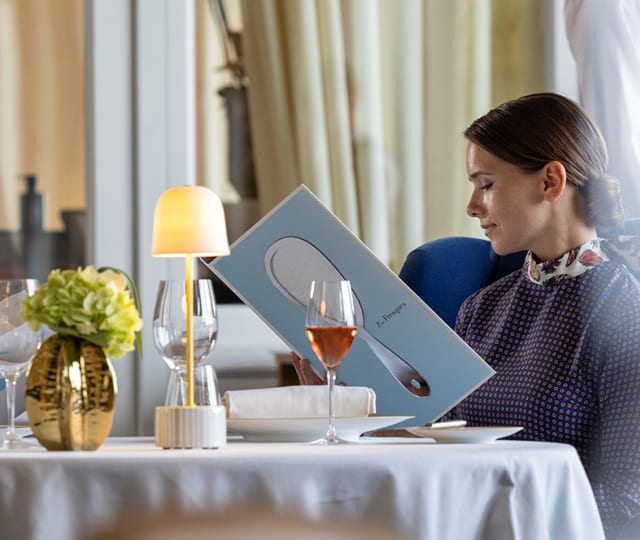 Femme lisant la carte du restaurant étoilé Les Fresques à l'Hôtel Royal Evian