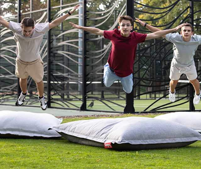 Trois jeunes sautant sur des FatBoys dans l'espace extérieur du Teen's Club au Kid's Resort