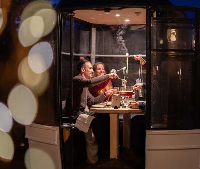 4 personnes mangeant de la fondue dans une télécabine le soir