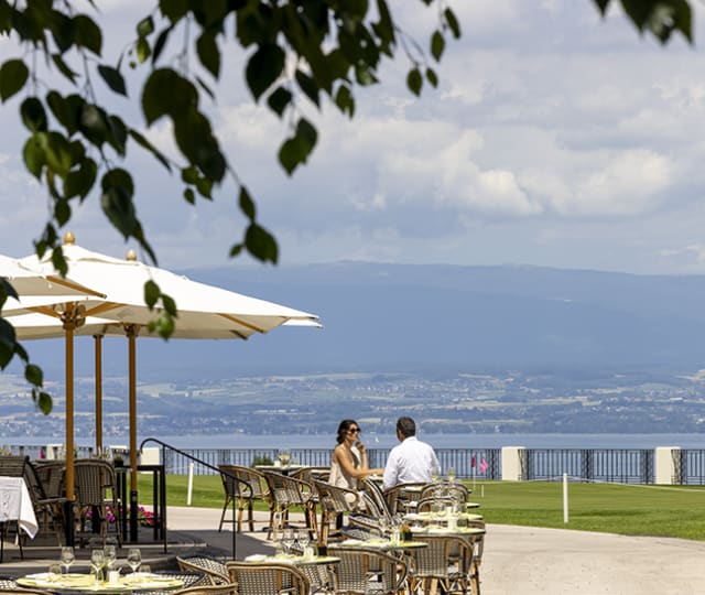 Hôtel Royal, hôtel 5 étoiles à Evian - Couple assis à une table du restaurant la Véranda de l'Hôtel Royal avec vue sur le Lac Léman