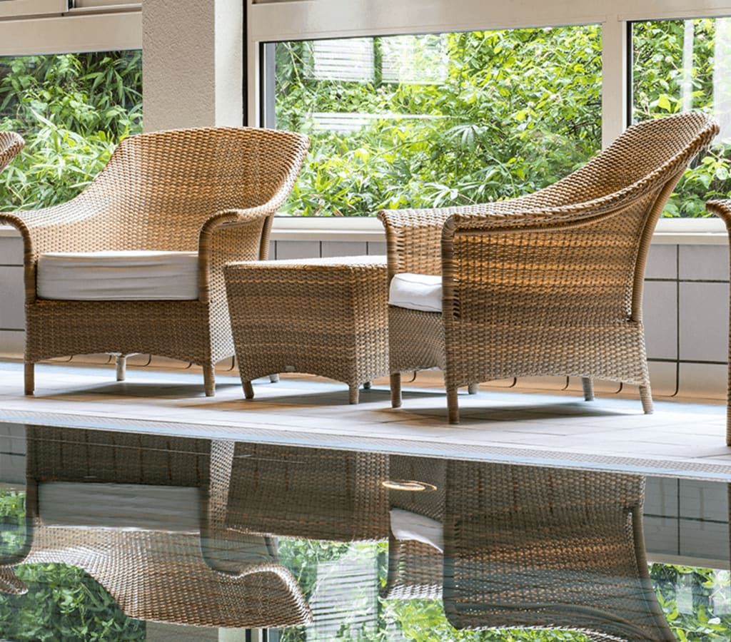 Piscine intérieure de l'Hôtel Ermitage avec ses fauteuils en osier pour se relaxer.