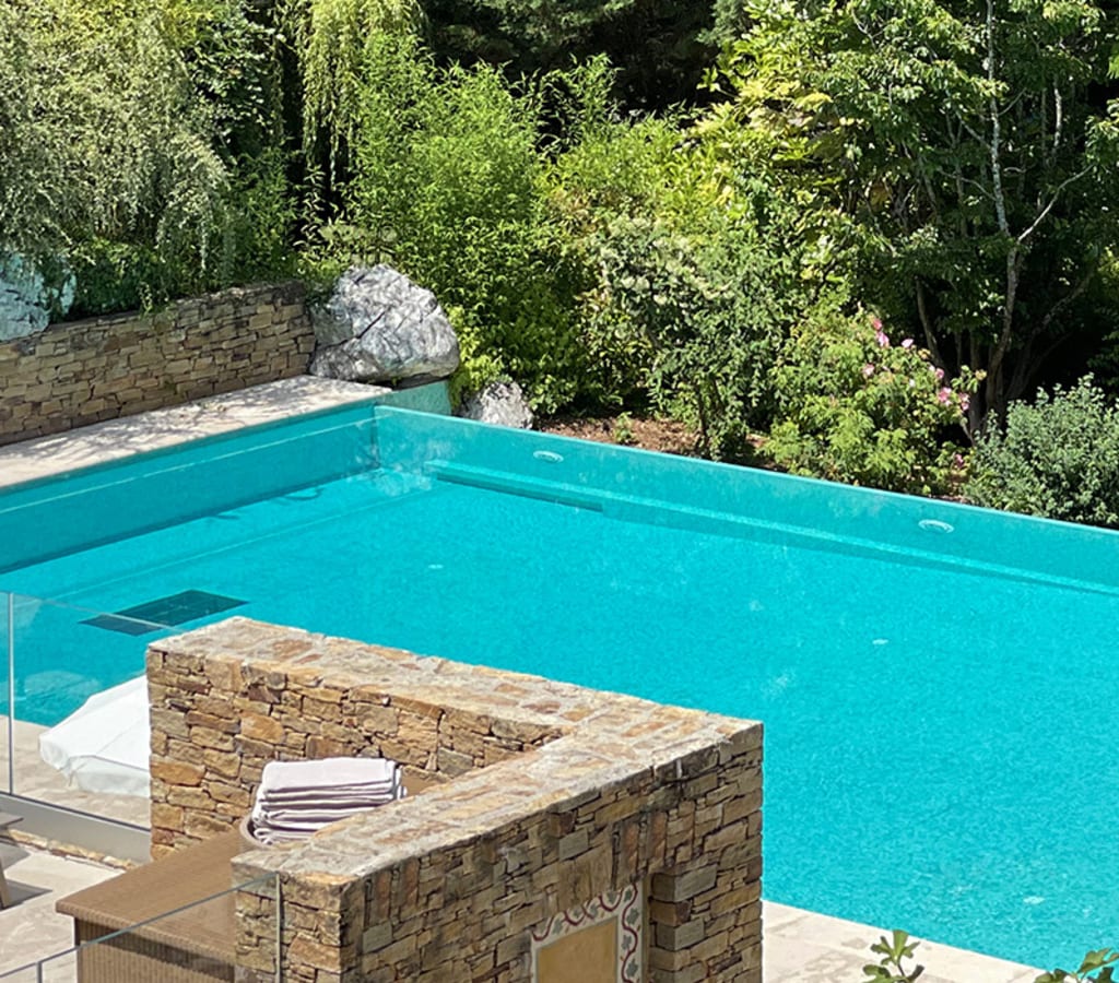 Vue de la piscine et du Pool Bar en pleine nature de l'Hôtel Ermitage avec un couple sortant de la piscine