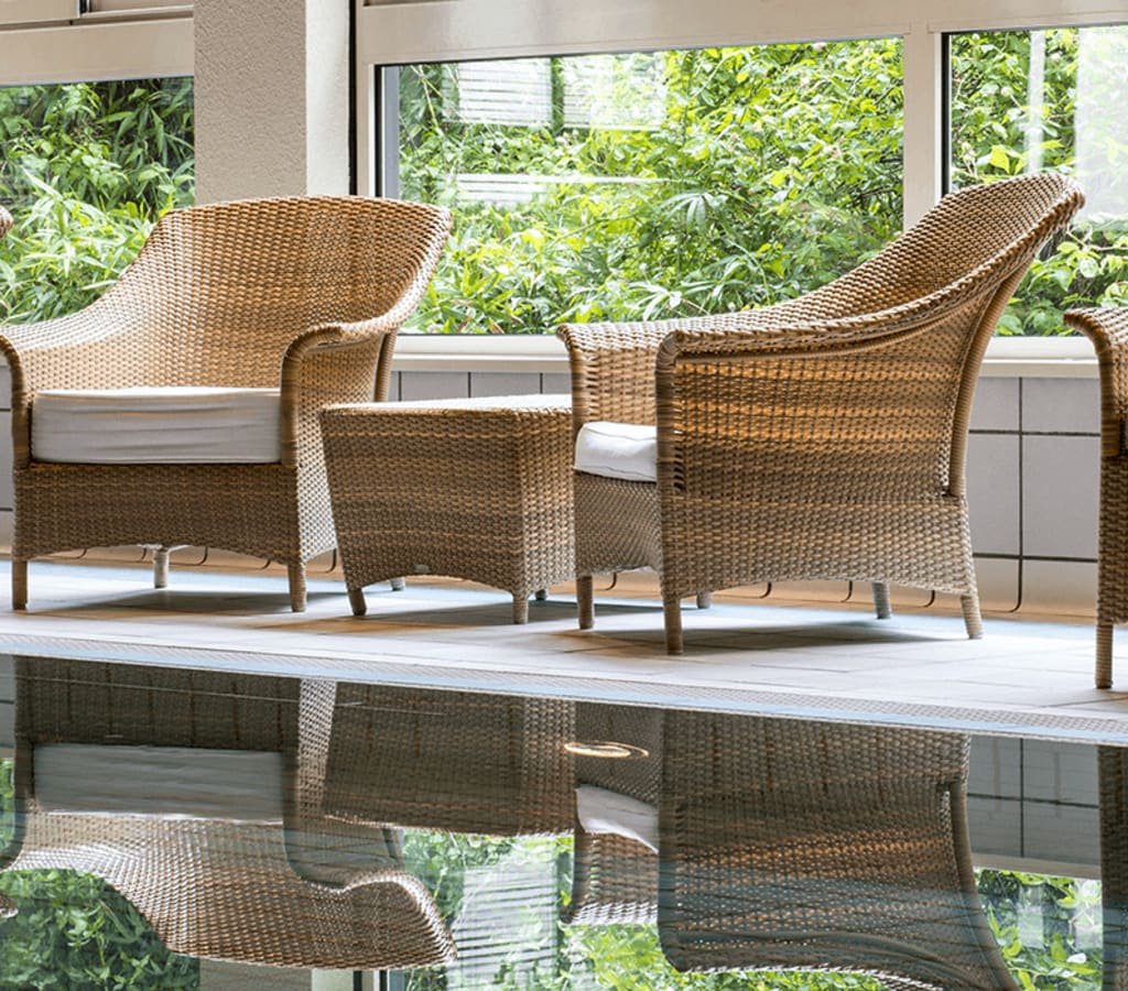 Piscine intérieure de l'Hôtel Ermitage avec ses fauteuils en osier pour se relaxer.