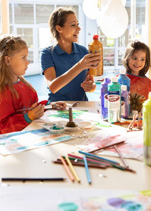 Deux petites filles qui font des travaux manuels et de la peinture avec une encadrante de l'équipe du Kid's Resort