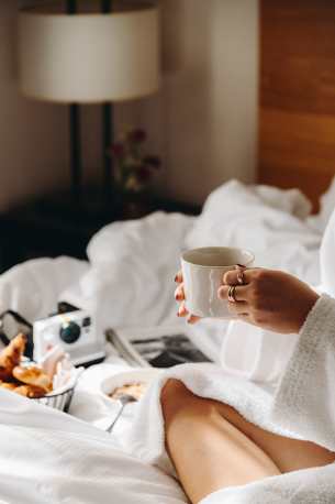 Hôtel Ermitage, 4 étoiles à Evian - Main de femme tenant une tasse à café sur un lit