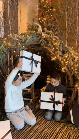 Deux enfants jouant avec des cadeaux de noël devant des décorations dans le salon de l'Hôtel Ermitage